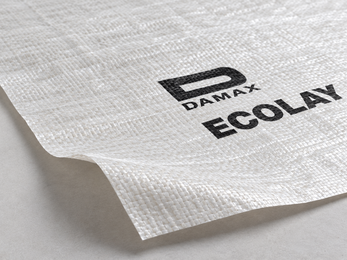 Close-up of the Ecolay membrane’s off-white woven texture, laminated surface and black product branding.